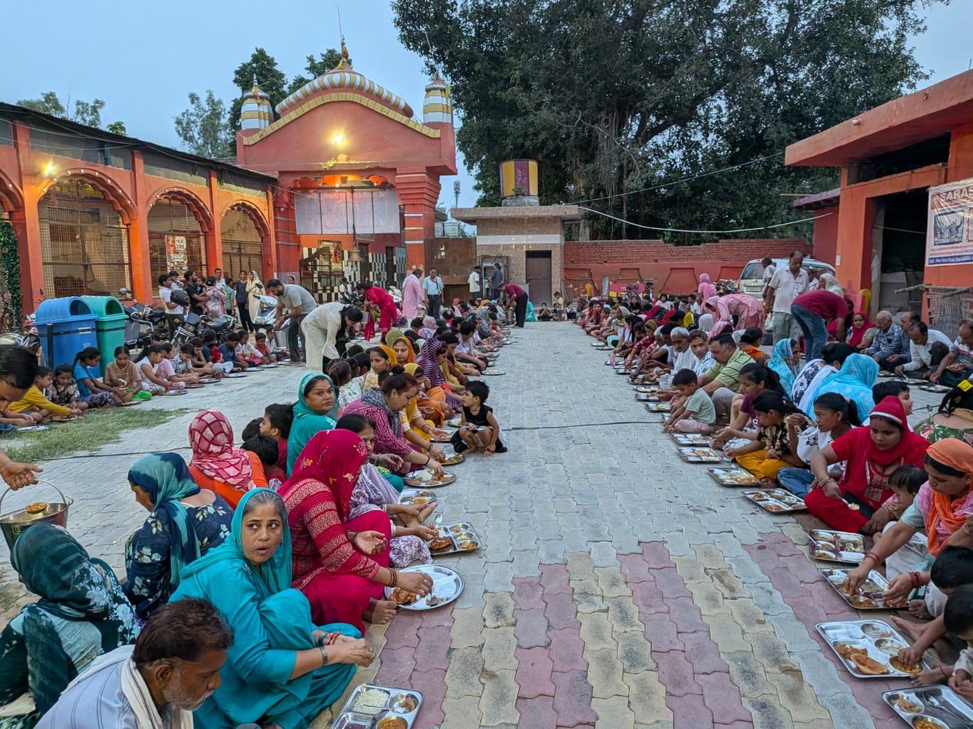 Girls and devotees seated in rows in the courtyard