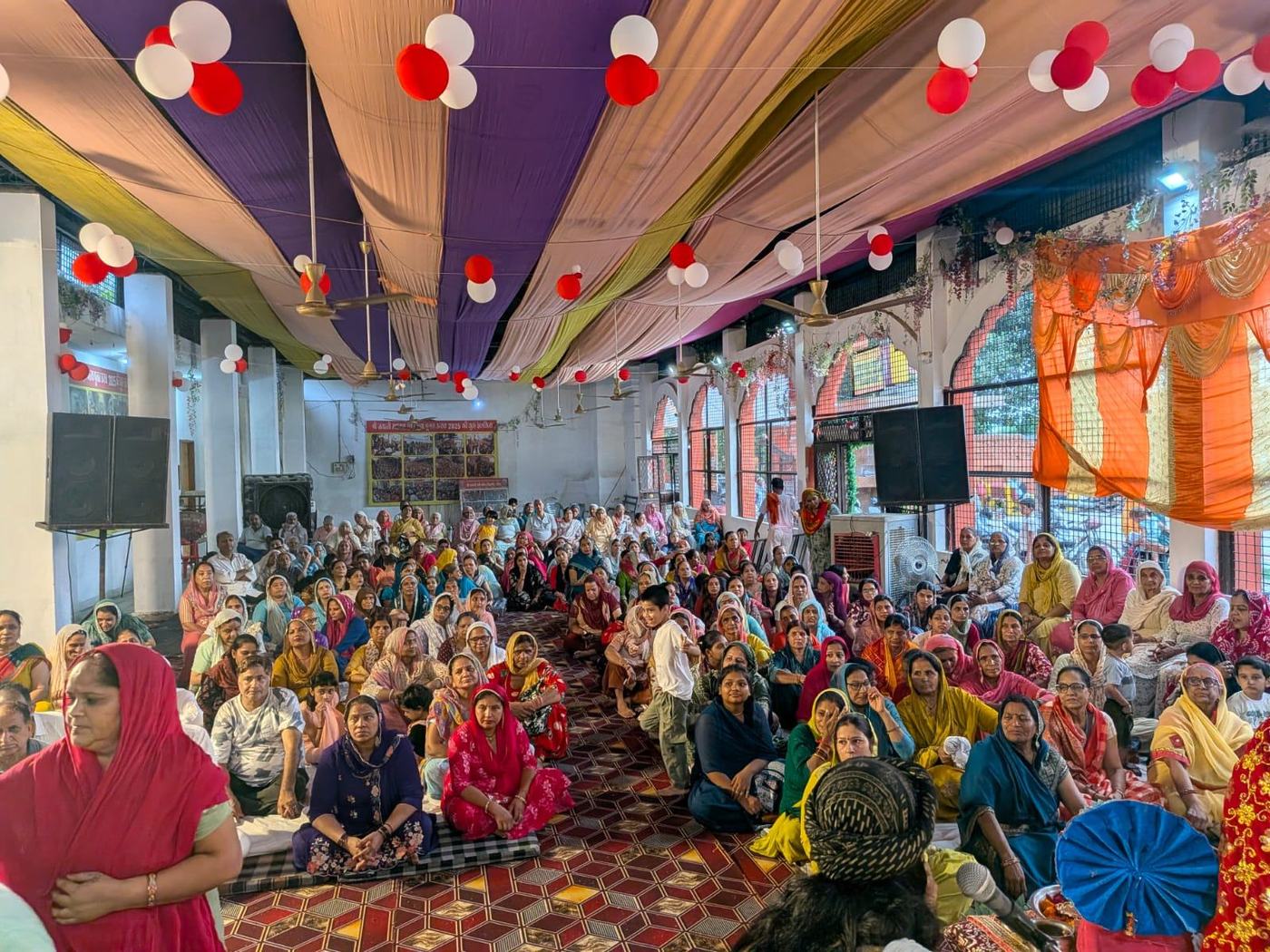 Devotees seated in the decorated hall of the mandir