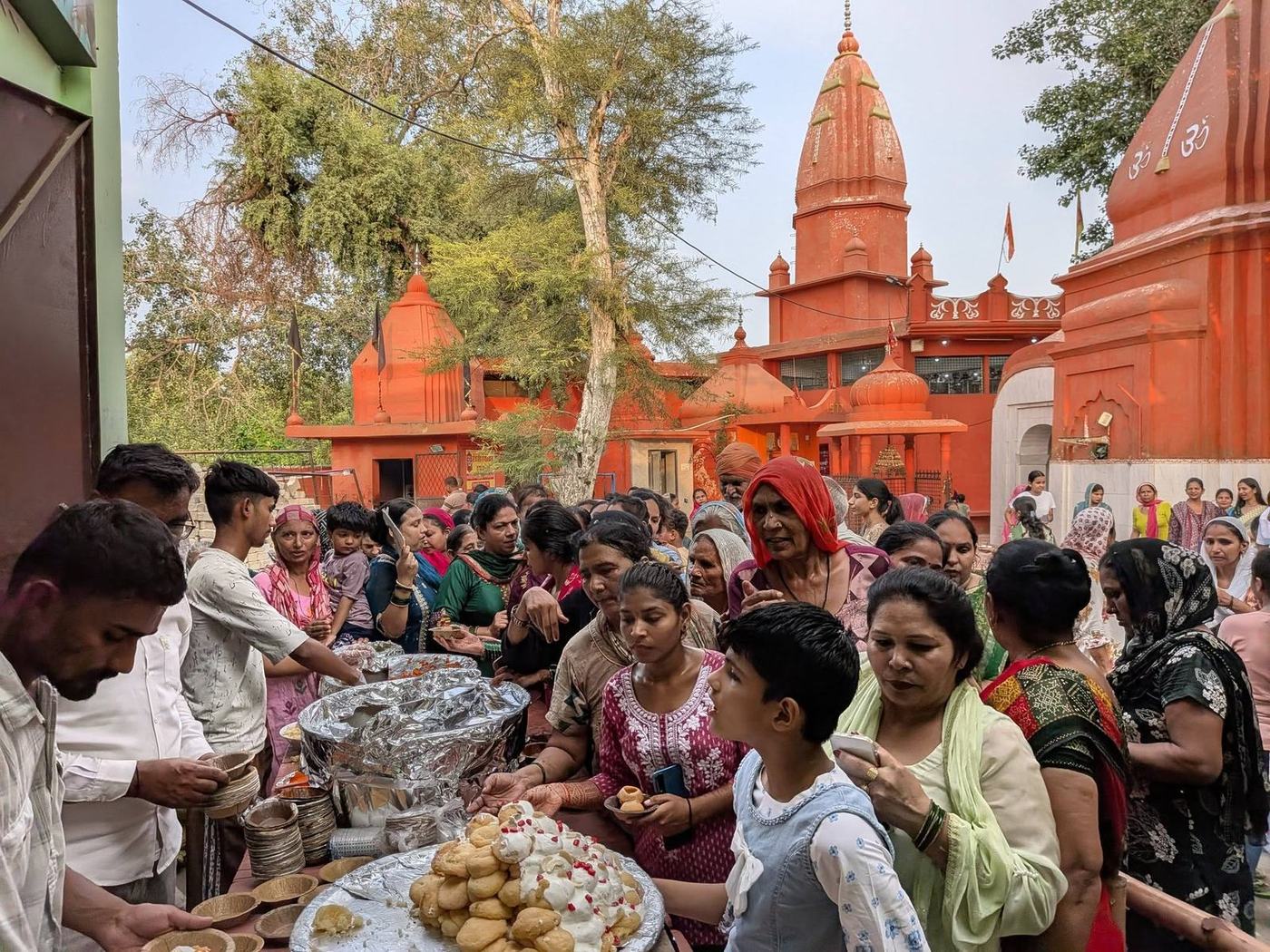 Devotees receiving prasad beside the temple shikhara